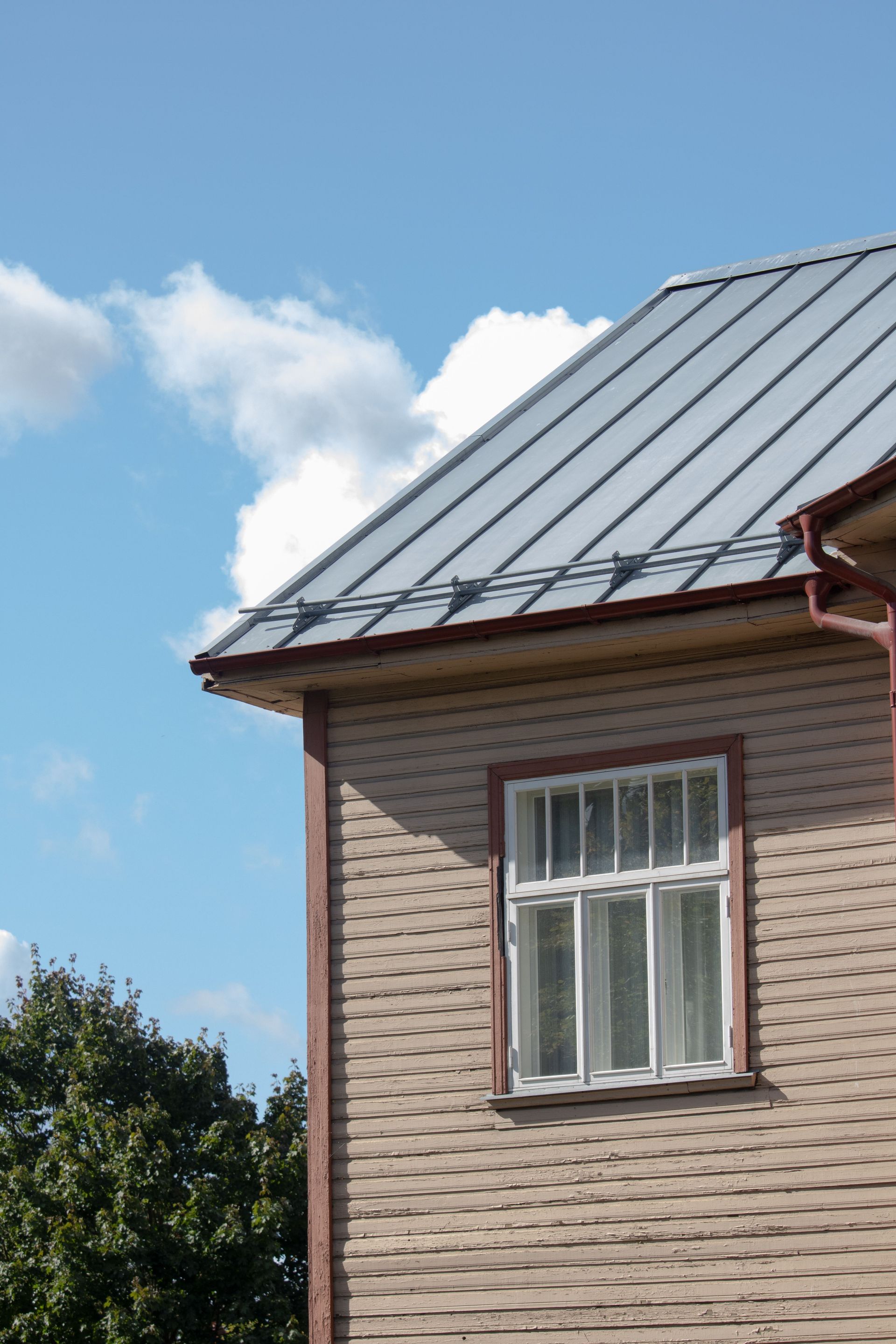 Close-up of a wooden building with metal roof and window in sunny Tartu, Estonia.